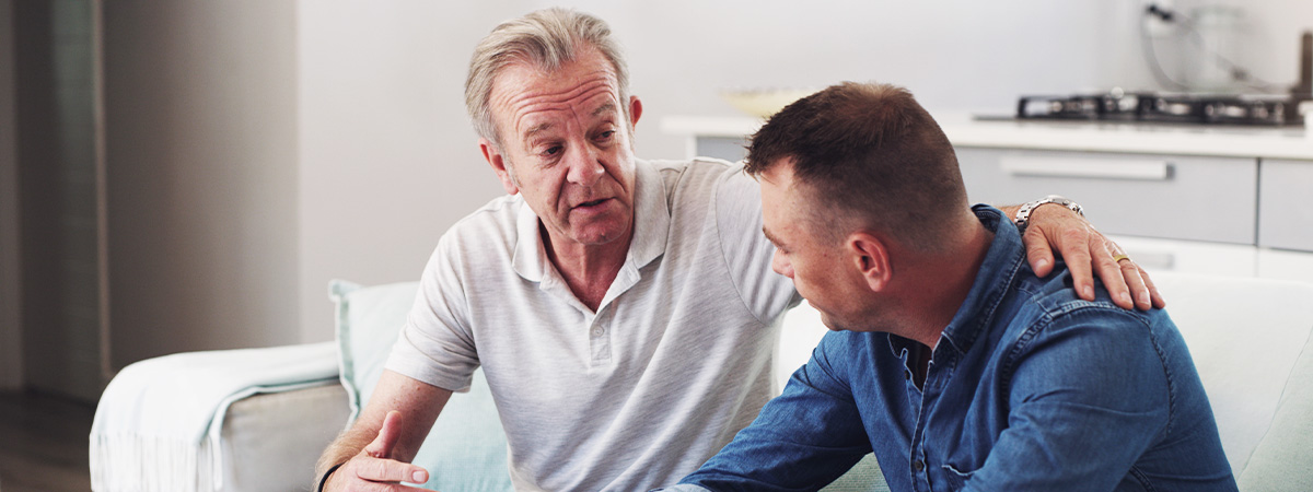 Father and son chatting on a couch about substance abuse.